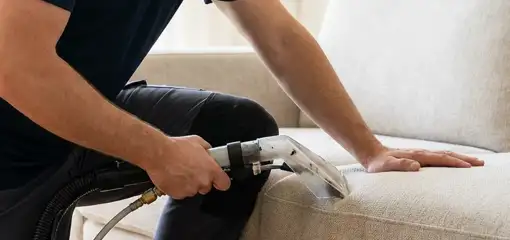 Professional upholstery cleaner deep-cleaning a fabric sofa with a handheld extraction tool, Peoria, IL.
